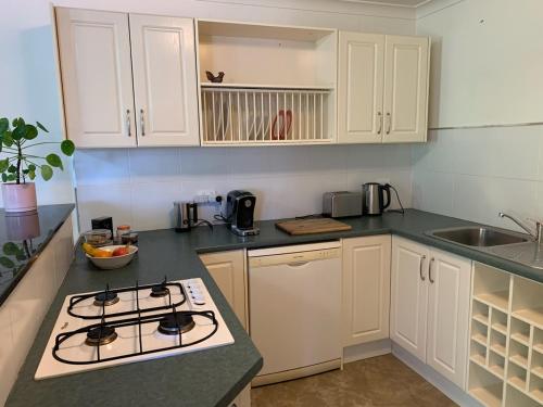 亚斯Very Comfortable Granny Flat的厨房配有白色橱柜和炉灶烤箱。