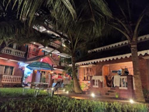 马尔万Blue Sea Beach Resort Malvan的夜晚在房子前面有一棵棕榈树