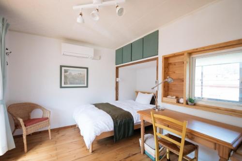 上田市Sun Terrace Bessho Onsen - Vacation STAY 21387v的一间卧室配有一张床、一张书桌和一个窗户。