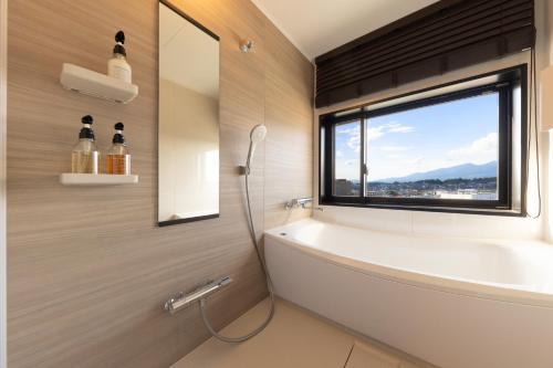 佐久市AQA Hotel Premium的带浴缸的浴室和窗户。