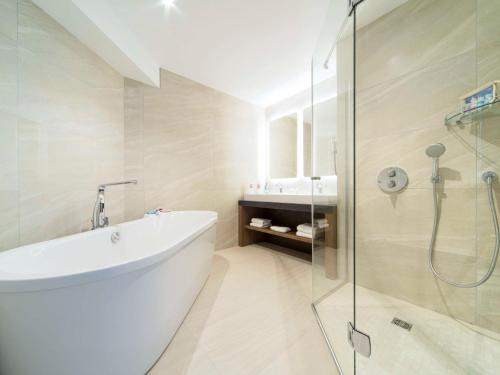 拉罗谢尔拉罗谢尔市中心宜必思尚品酒店的带浴缸和玻璃淋浴间的浴室。