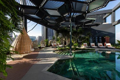 吉隆坡Hotel Indigo Kuala Lumpur on the Park, an IHG Hotel的一座带遮阳篷的建筑屋顶上的游泳池