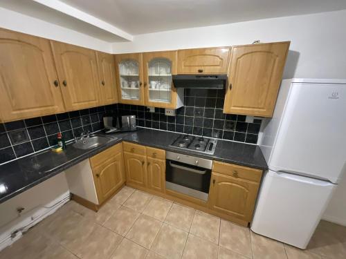 伦敦Spacious 2 bed Dulwich flat green views的厨房配有木制橱柜和白色冰箱。