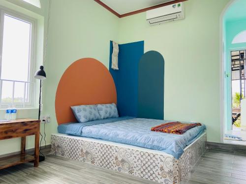 Ấp Khánh Phước (1)Gió Homestay and Coffee的一间卧室配有一张橙色和蓝色墙壁的床