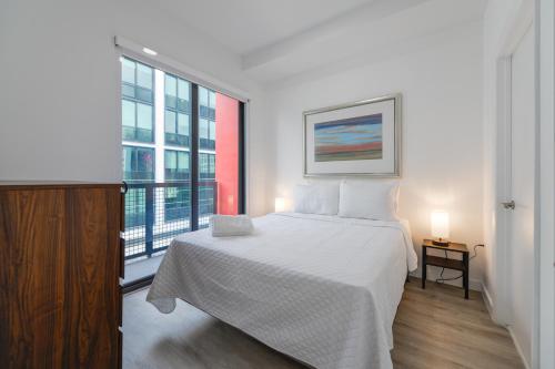 迈阿密Comfortable Apartment in Charming Wynwood的卧室设有白色的床和大窗户