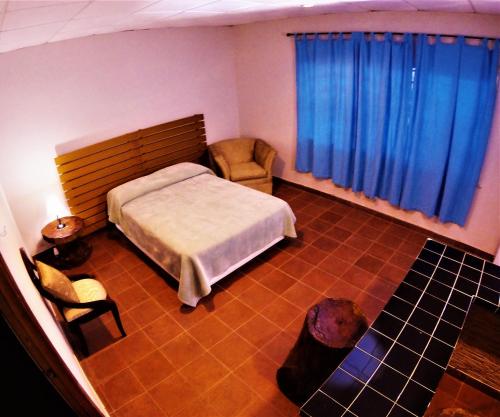 科隆Hacienda Alajuela的一间卧室配有一张床、一把椅子和蓝色窗帘