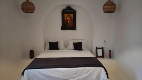Maison d’hôte, Djerba的卧室配有带黑色枕头的白色床