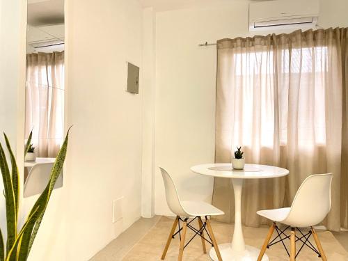 杜马格特Japandi-inspired Hideaway的白色的用餐室配有桌椅