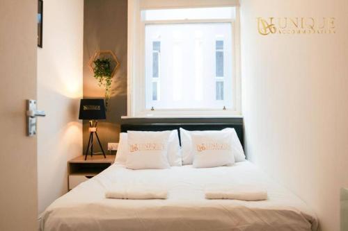 利物浦Luxury 2-bed Haven in Liverpool的卧室配有一张带白色枕头的床,卧室设有窗户