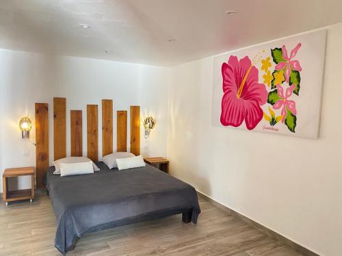 圣弗朗索瓦卡乐巴斯旅馆的卧室配有一张床,墙上挂有绘画作品