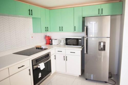 尼格瑞尔Irie Vibes Ocean View的厨房配有绿色橱柜和不锈钢冰箱