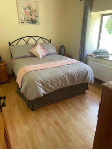卡斯尔格雷戈里Castlegregory-Seaside 2 Bedroomed Cottage的卧室内的一张床位,铺有木地板
