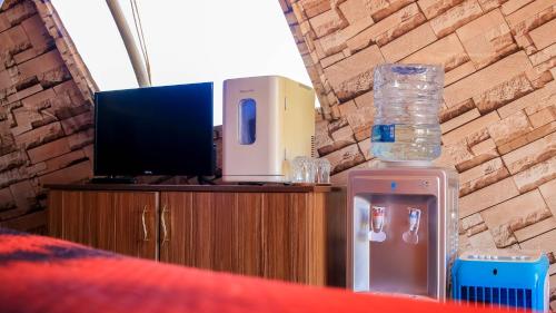 安博塞利Little Amanya Camp Amboseli的一间卧室配有电视和一个带玻璃瓶的梳妆台