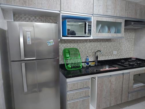 索莱马Cantinho de vó - Praia Grande - Aviação的厨房配有不锈钢冰箱和水槽
