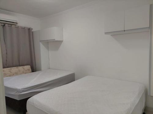 索莱马Cantinho de vó - Praia Grande - Aviação的配有白色墙壁的小客房内的两张床