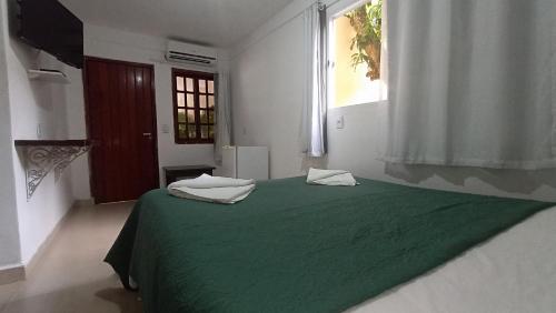 沙帕达-杜斯吉马朗伊斯Pousada do Didi Chapada dos Guimaraes.的白色客房的一张绿色床,设有窗户