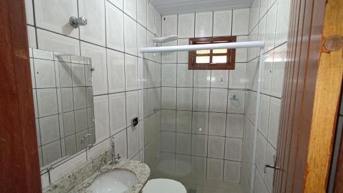 沙帕达-杜斯吉马朗伊斯Pousada do Didi Chapada dos Guimaraes.的白色瓷砖浴室设有卫生间和淋浴。