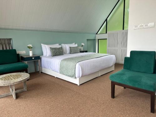 DimbulaHummingbird St.Clare Villas的一间卧室配有一张床和两张绿色椅子