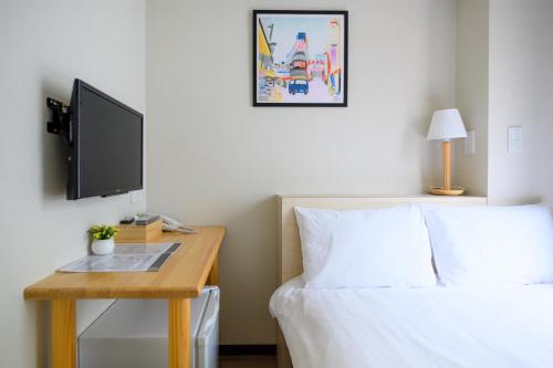 东京Ueno Woo Hotel的一间卧室配有一张床和一张书桌及电视