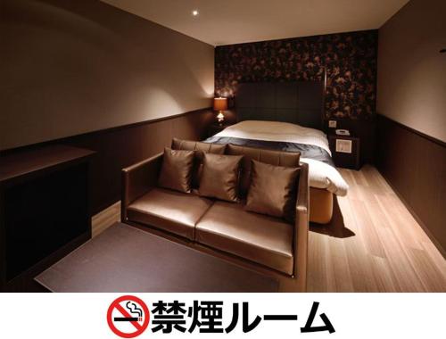 名古屋Hotel LALA - Kitashiga - (Adult Only)的一间卧室配有一张床和一张皮沙发