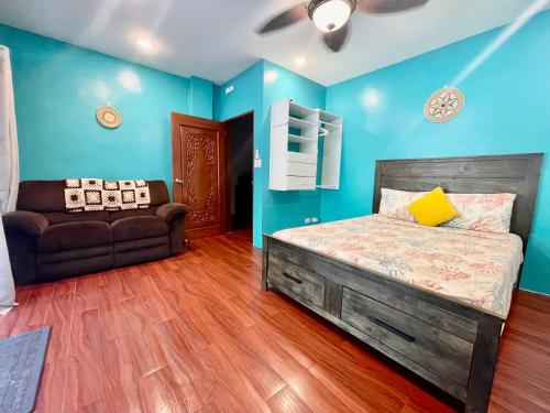 科罗尔Ngermid Oasis- 2 BD Master Suite的卧室拥有蓝色的墙壁,配有一张床和一张沙发