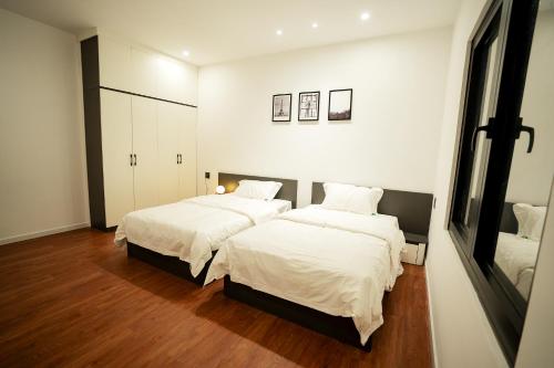 槟知Heddin Homestay的一间卧室配有两张带白色床单和木地板的床。