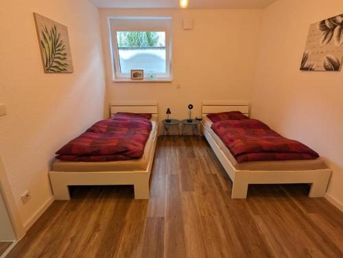 威斯巴登Moderne Neubau Ferienwohnung的客房内设有两张床,铺有木地板,设有窗户。