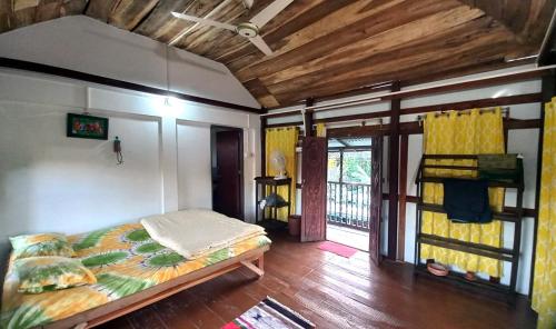 斯里曼加尔乌帕齐拉Oronner Din Ratri的一间带一张床的卧室,位于带木制天花板的房间内
