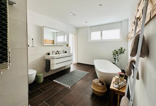 ErmatingenHaus am Bodensee mit Sicht - Stilvoller Luxus的浴室配有盥洗盆、卫生间和浴缸。