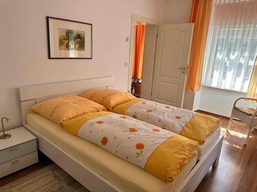 萨斯尼茨Ferienwohnung Seerose的一间卧室配有一张黄色和橙色床单。