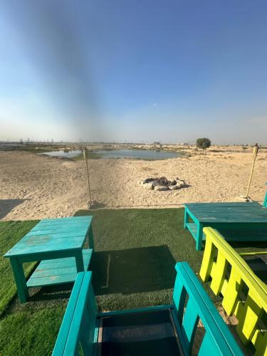 迪拜Oasis Caravan的海滩旁的两张蓝色和黄色的桌椅