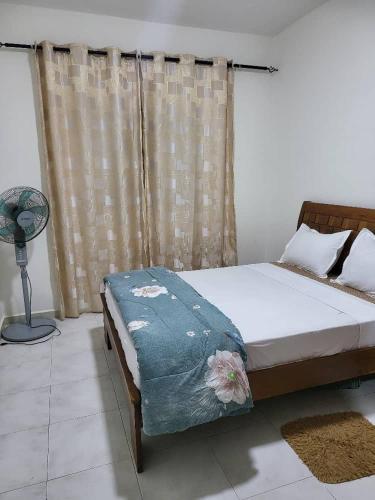 达喀尔JADO House的一间卧室配有一张床和一个带风扇的窗户。