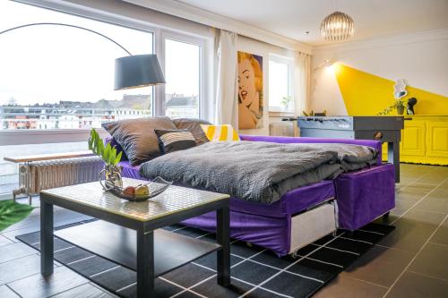 科布伦茨Pop Art Loft über den Dächern von Koblenz的一间卧室配有一张紫色的床和一张桌子