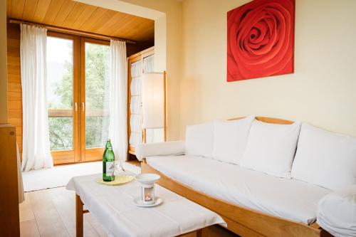 塞默灵Panoramahotel Wagner - Das Biohotel am Semmering的客厅配有白色沙发和红玫瑰