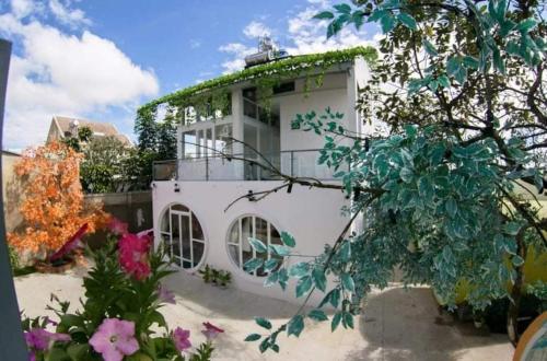 大叻Da Lat LUCINA Boutique Hotel的白色房子,带花卉的绿色屋顶