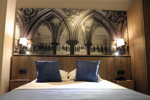 圣米歇尔山特拉斯布拉德酒店的一间卧室配有一张带两个蓝色枕头的床