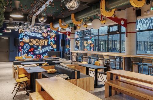 勒阿弗尔JOST Hôtel Le Havre Centre Gare的一间带木桌和椅子的餐厅以及壁画