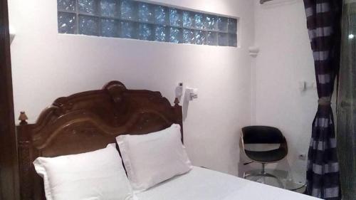布拉柴维尔Villa takamelouer immo的一间卧室配有一张带木制床头板和椅子的床。