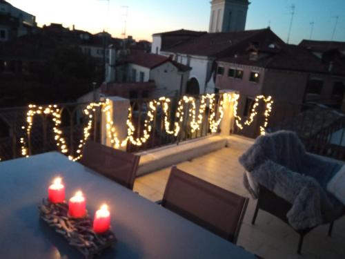 威尼斯VENICE HOLIDAY TERRACE的阳台上的一张桌子上放两个蜡烛,配有灯