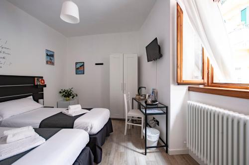 莱科La Casa del Sarto - Rooms and Apartments的配有书桌和窗户的客房内的两张床