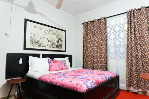 KasoaVillage Francophone Hotel的一间卧室配有一张带粉红色床单和窗帘的床