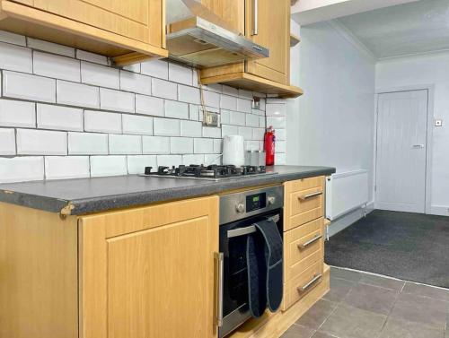 查塔姆Home In Medway的厨房配有木制橱柜和炉灶烤箱。