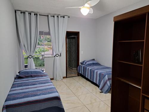 安格拉杜斯雷斯Casa aconchego Parque Mambucaba的一间卧室设有两张床,窗户配有窗帘