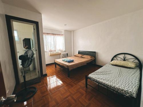 苏里高Bayan’s 2 storey apartment的小房间设有两张床和风扇