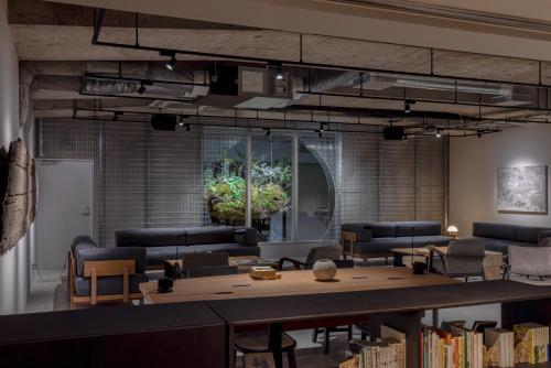 京都RAKURO Kyoto by THE SHARE HOTELS的带沙发和书籍桌子的图书馆