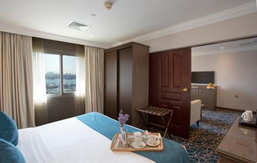 迪拜卡尔顿塔酒店的一间酒店客房,配有床和一张桌子,上面有杯子