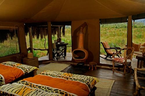 卡拉图Crater Forest Tented Lodge的一间设有两张床的客房和一个位于帐篷内的壁炉