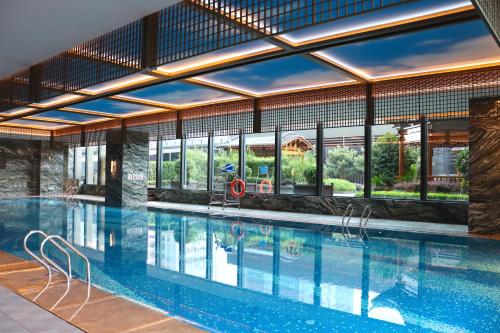 西安西安高新 JW 万豪酒店的一座大型游泳池,位于一座带窗户的建筑内