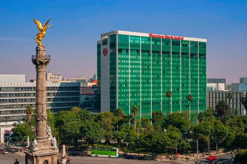 墨西哥城玛利亚伊莎贝尔墨西哥城喜来登酒店的一座高大的绿色建筑,前面有雕像