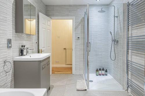 水上伯顿Charming 3BD Cotswolds Family Retreat的带淋浴和盥洗盆的浴室